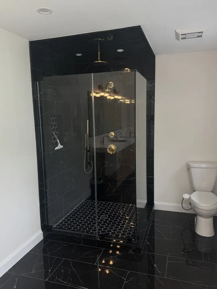 Frameless glass shower with black hardware, installed by IDEAL Shower Doors