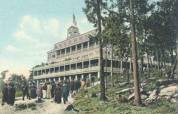 People walking toward large historic hillside hotel