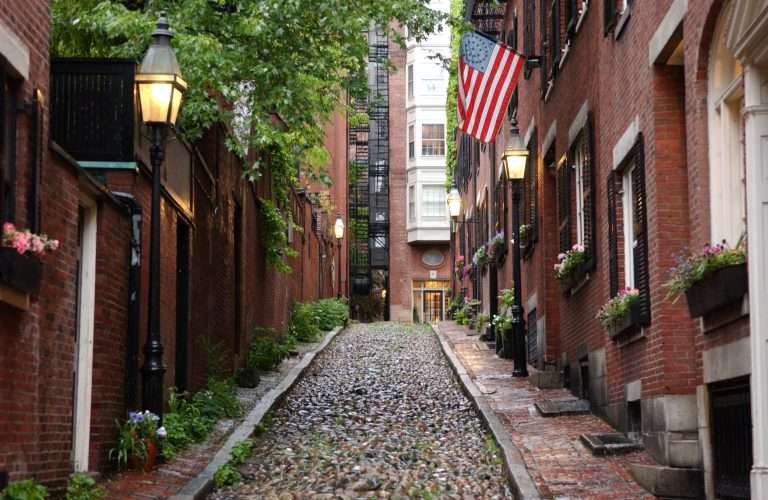 Historic cobblestone alley with brick buildings and American flag