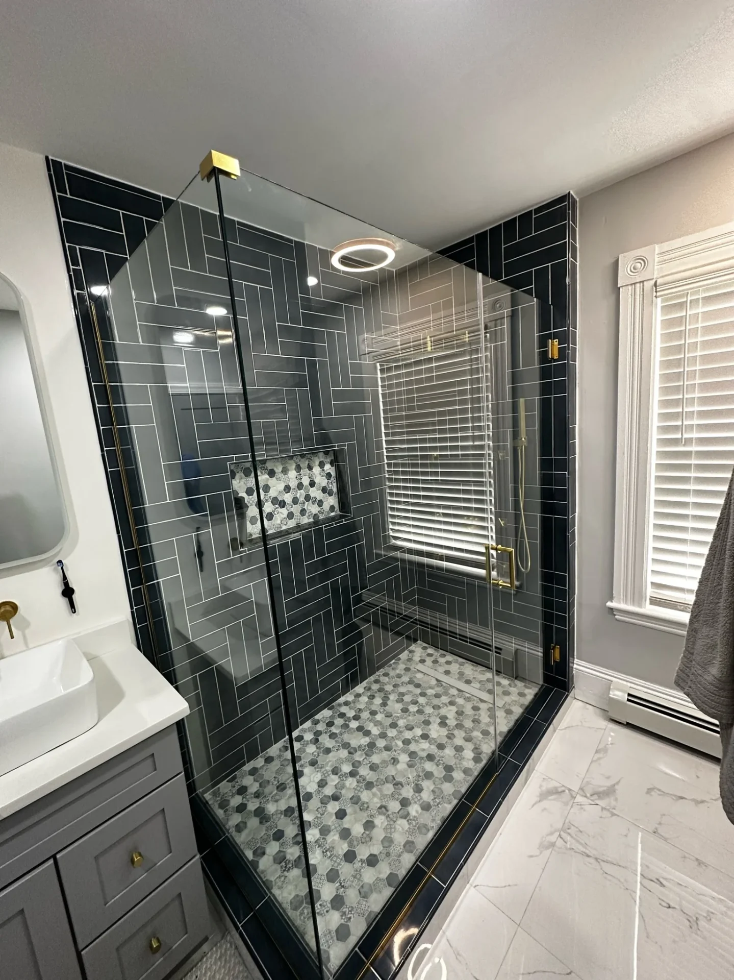 frameless pivot shower door brushed gold herringbone black tile Saugus MA