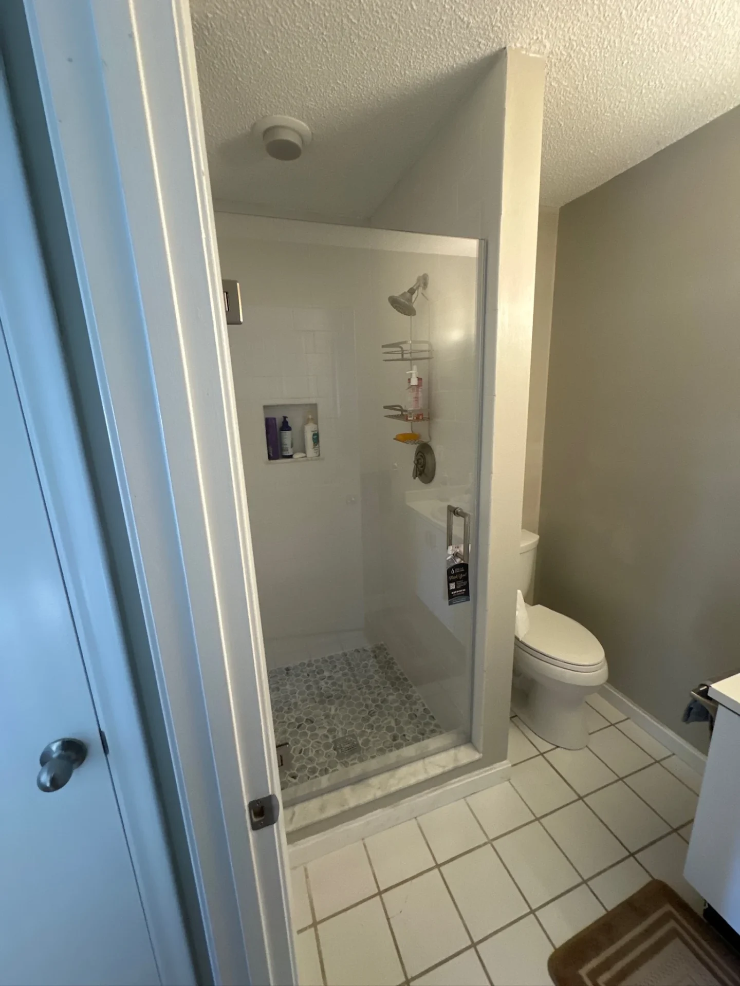 frameless hinged pivot shower door white surround pebble floor Bow NH