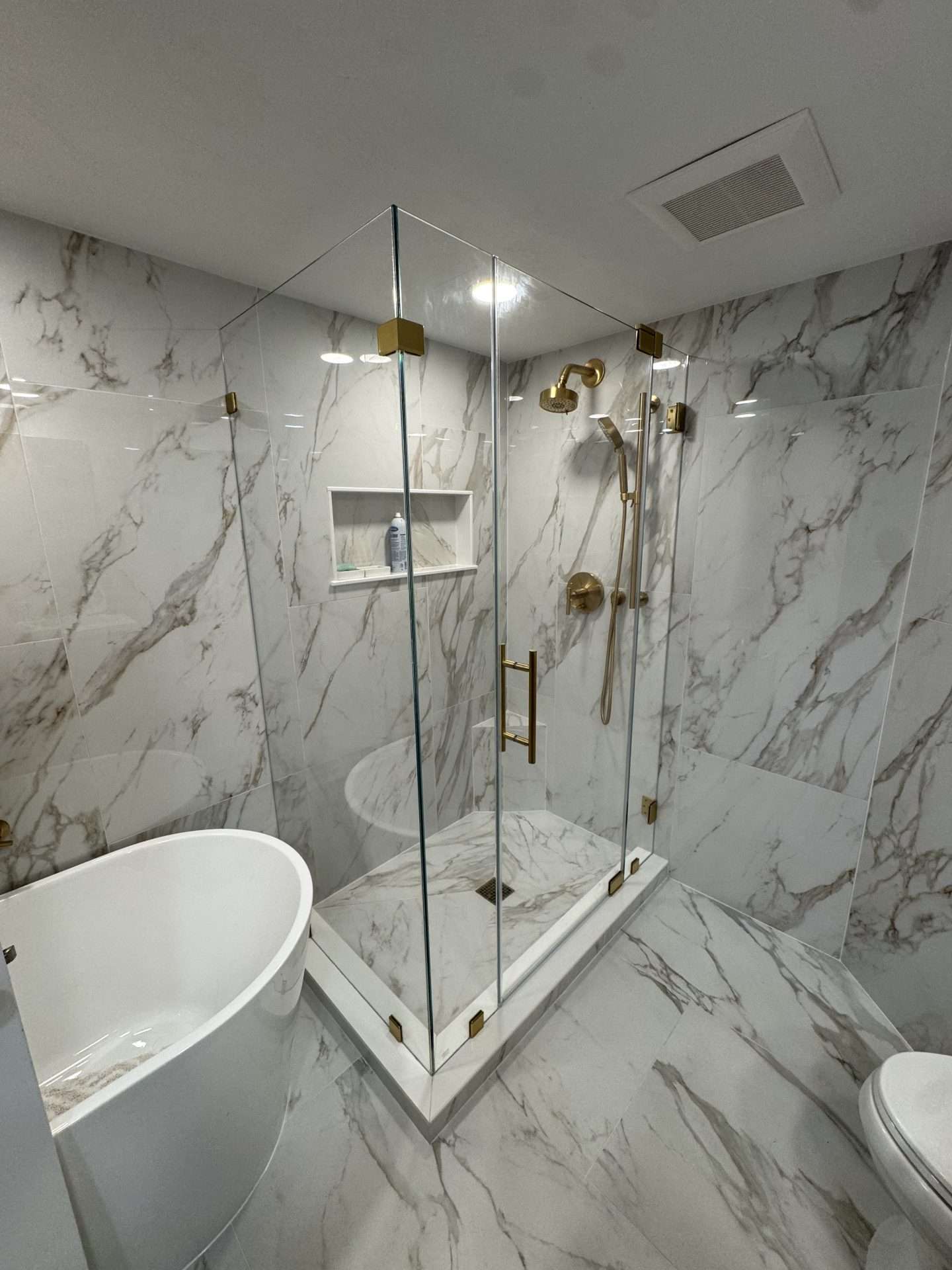 Calacatta marble frameless glass shower enclosure with gold hardware and built-in niche, Salem MA