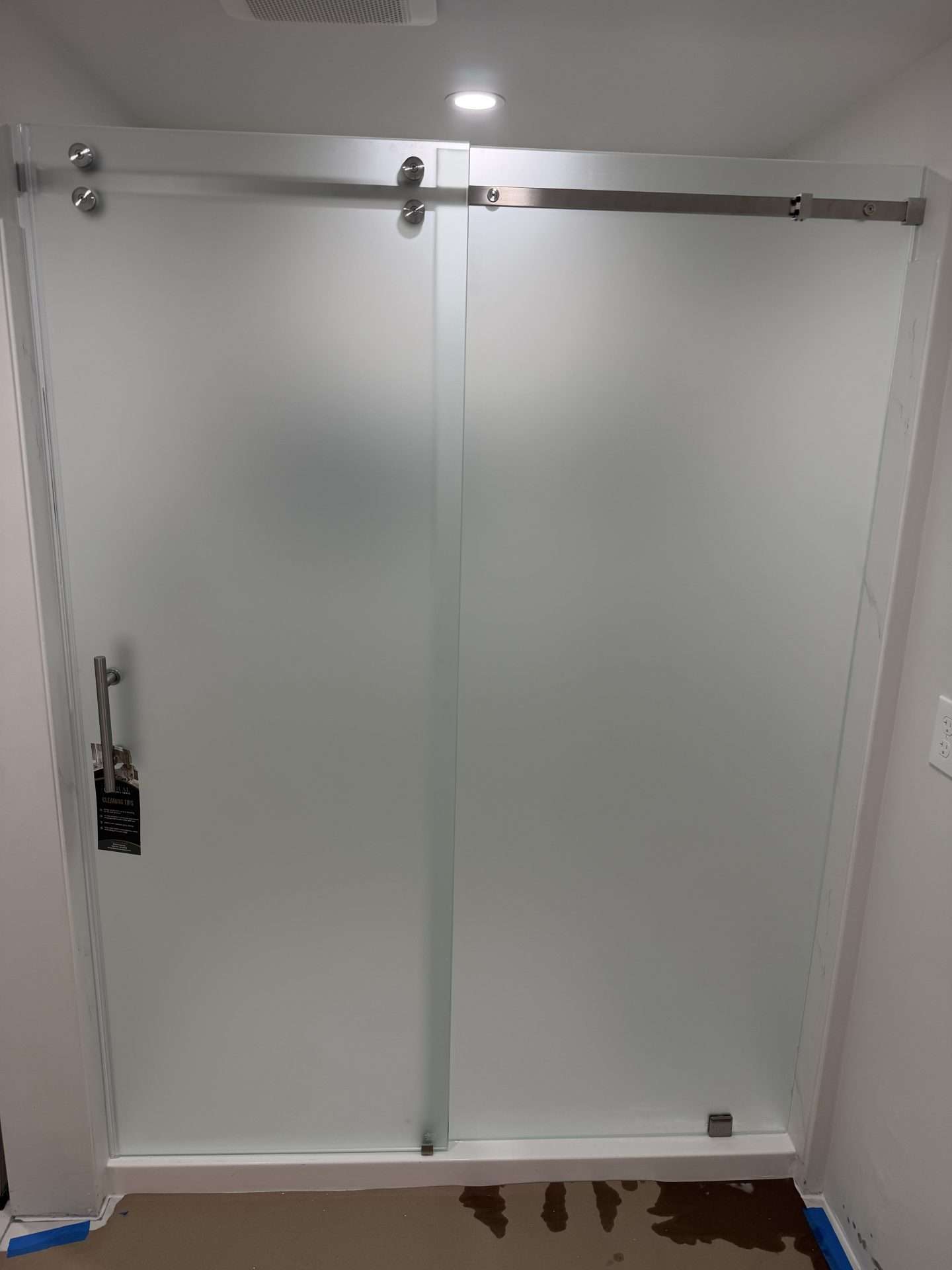 Frosted glass frameless shower enclosure with brushed nickel barn-style hardware and clean finishes