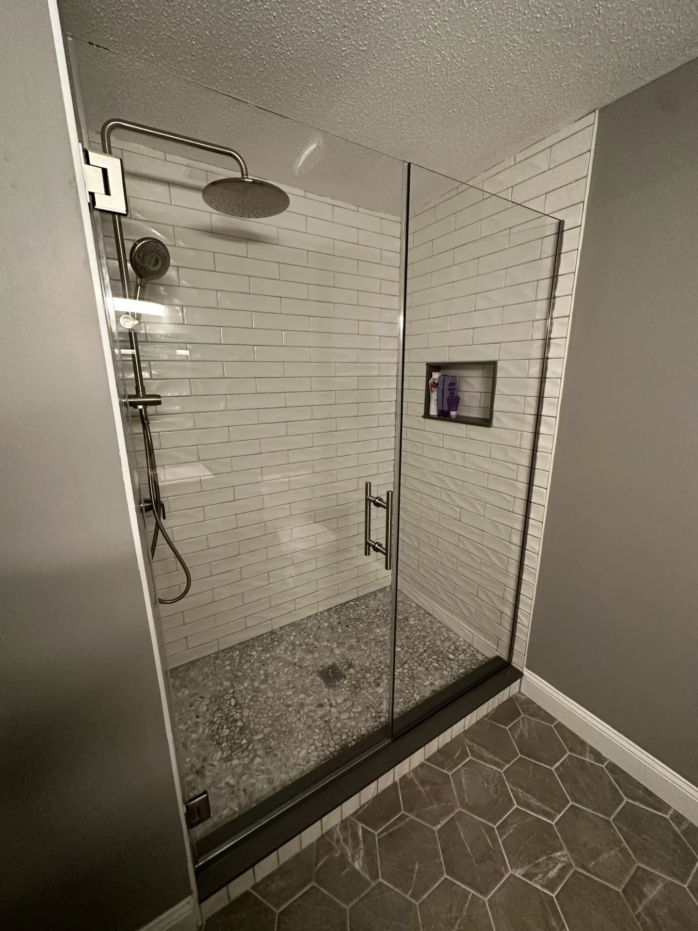 Frameless pivot door matte black hardware white subway tile Beverly MA