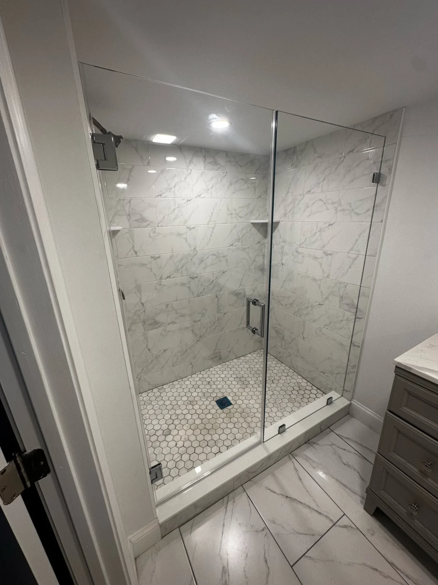 Frameless pivot shower door chrome marble-look porcelain hex floor Revere MA