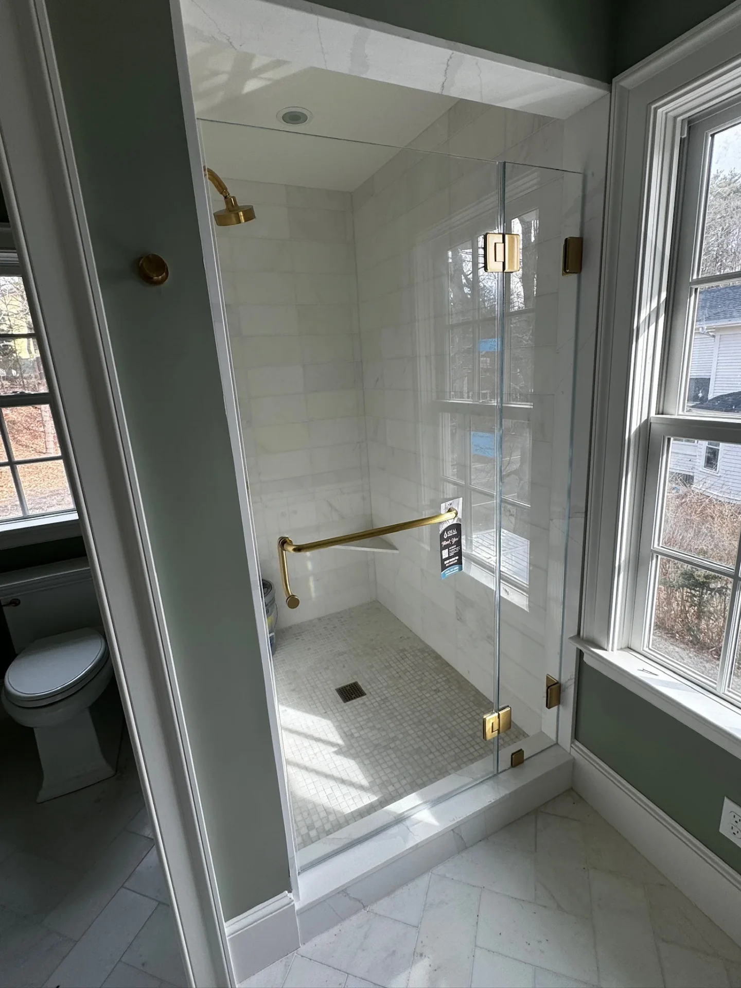 Frameless pivot door brushed gold hardware marble tile herringbone Manchester-by-the-Sea MA