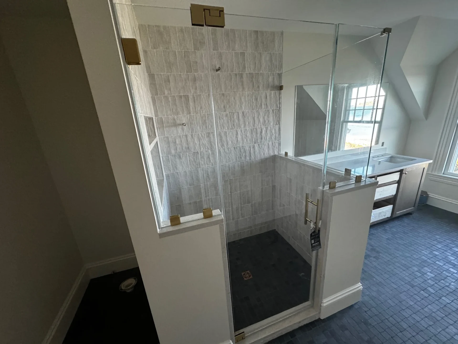 Frameless corner shower brushed gold hardware gray stacked tile dark floor Beverly MA