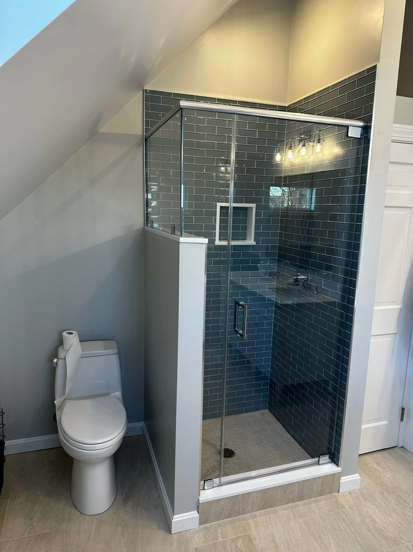 frameless chrome pivot shower door deep teal subway tile sloped dormer ceiling Marblehead MA