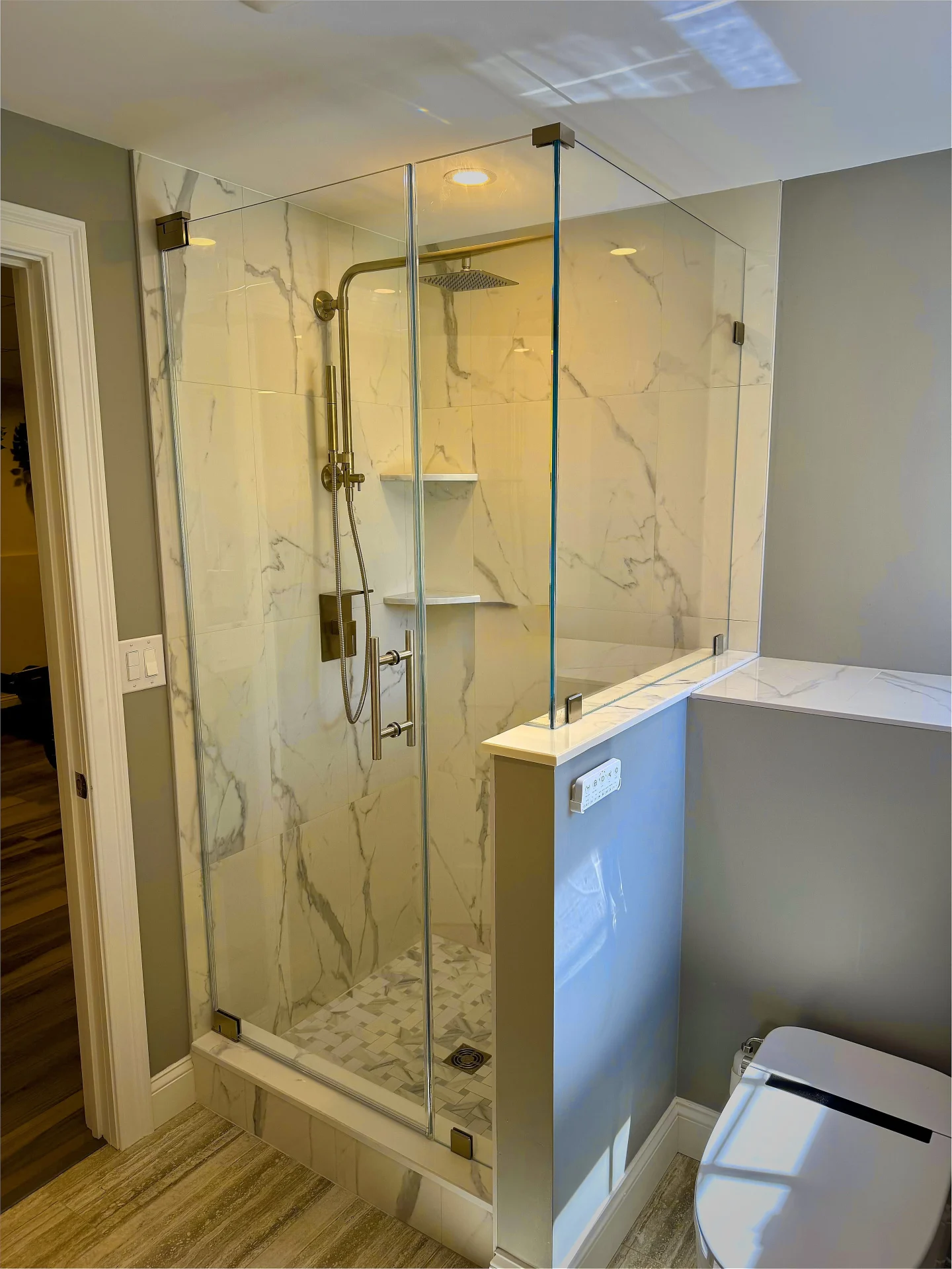 Frameless corner shower brushed bronze hardware calacatta tile Dracut MA