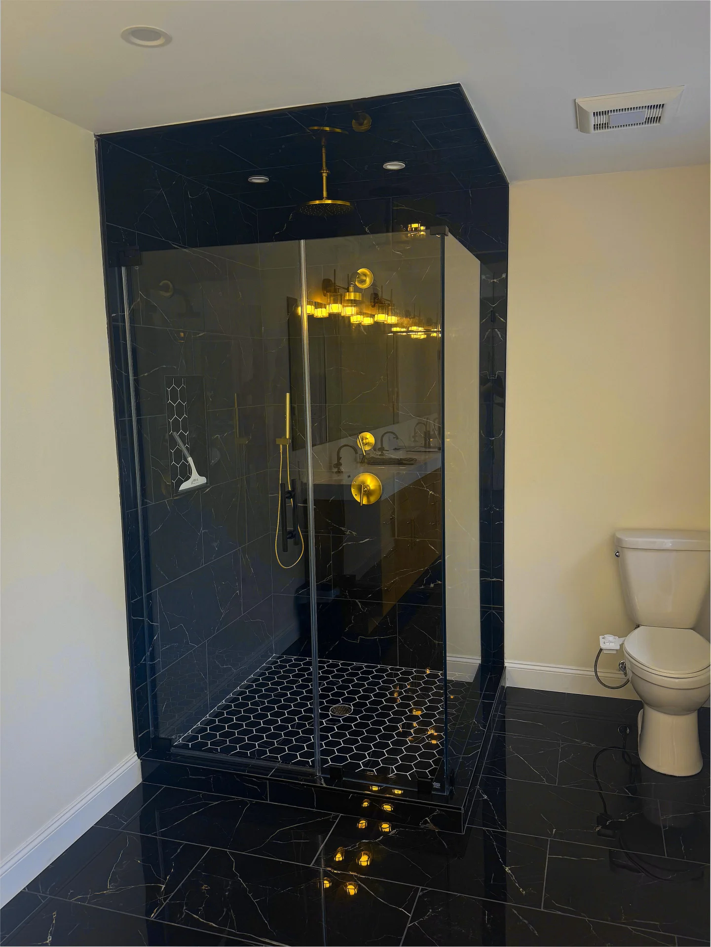 frameless corner shower enclosure brass hardware black marble tile North Shore MA