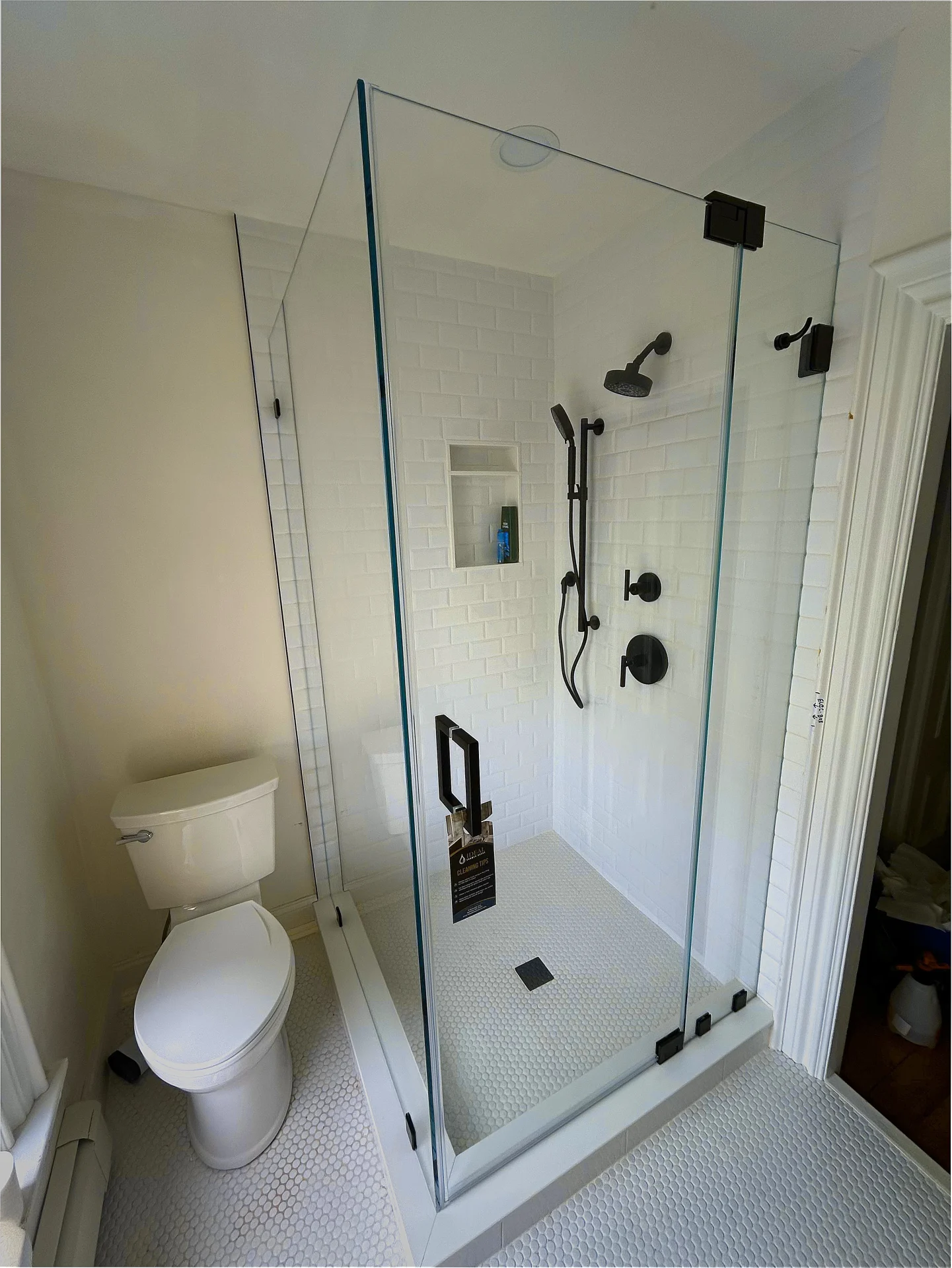 Corner frameless shower enclosure with matte black hardware and white subway tile in Boston MA