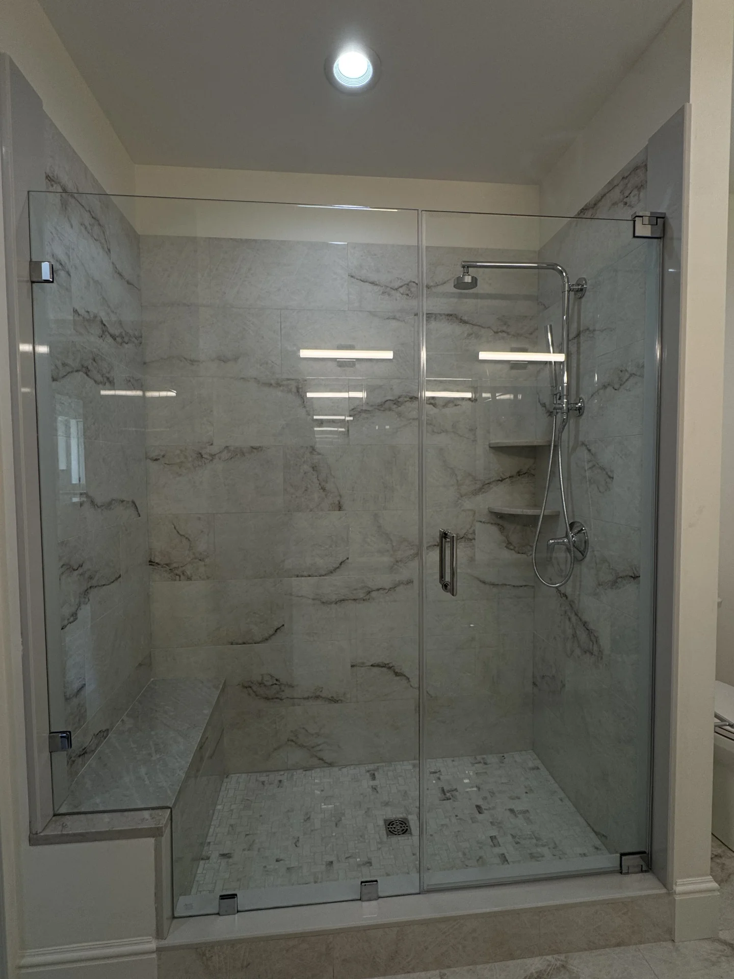Frameless hinged shower door, chrome hardware, marble-look tile, Bedford MA