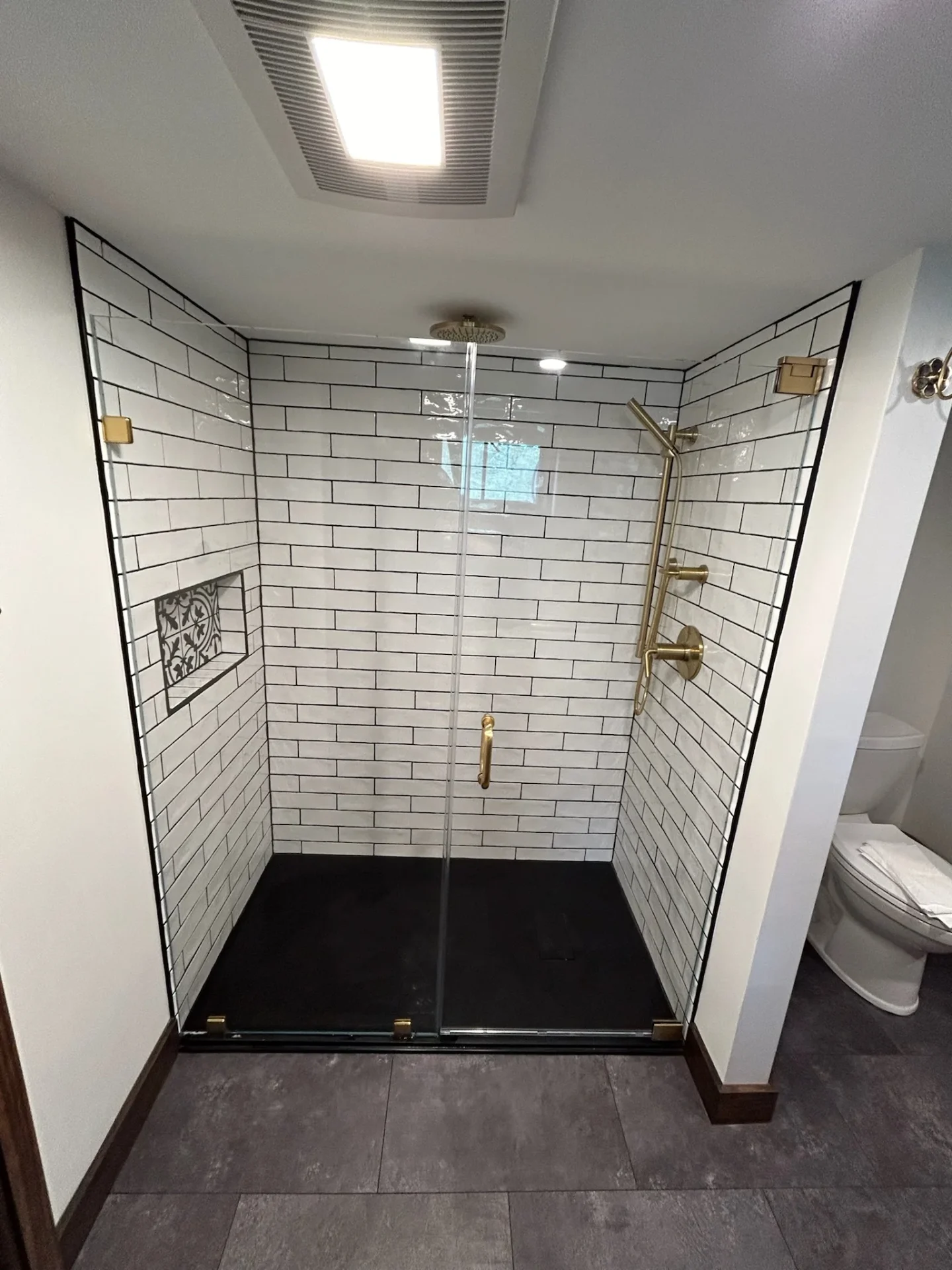 Frameless hinged enclosure, brushed gold hardware, white subway tile, Ayer MA