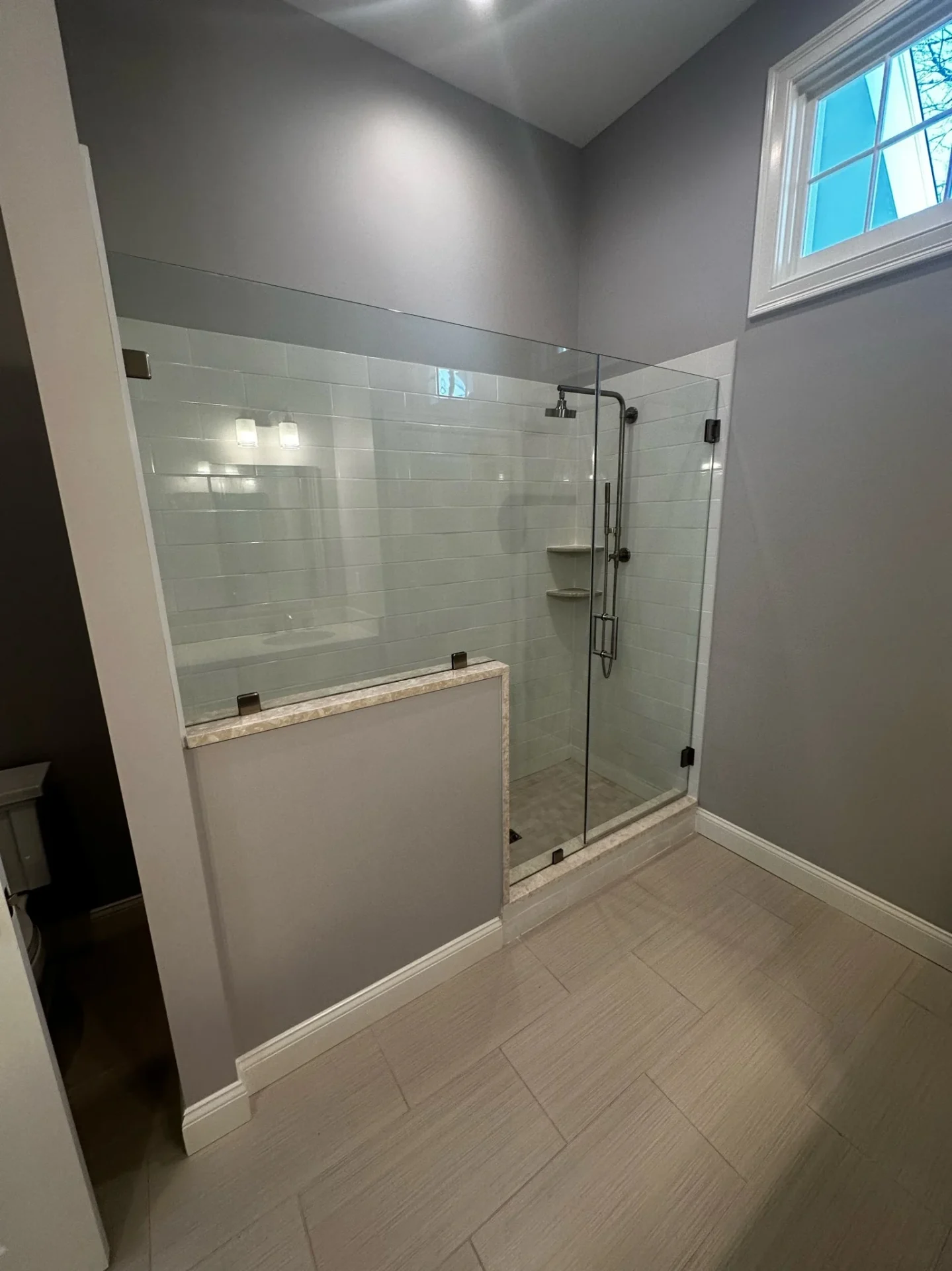 Frameless shower door with matte black hardware and white subway tile in Reading, MA