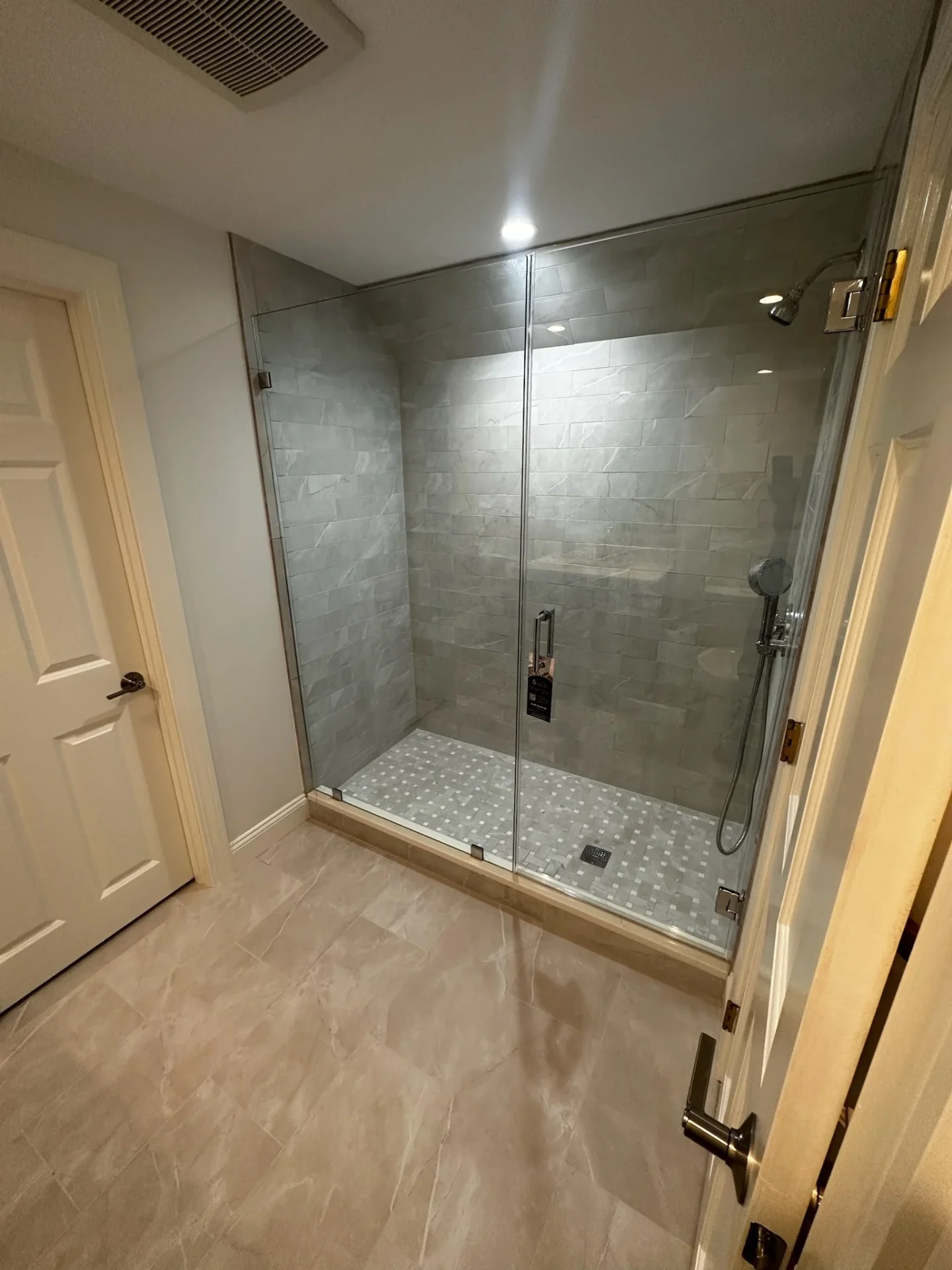 Frameless walk-in shower with header bar and marble tile in Boxford MA