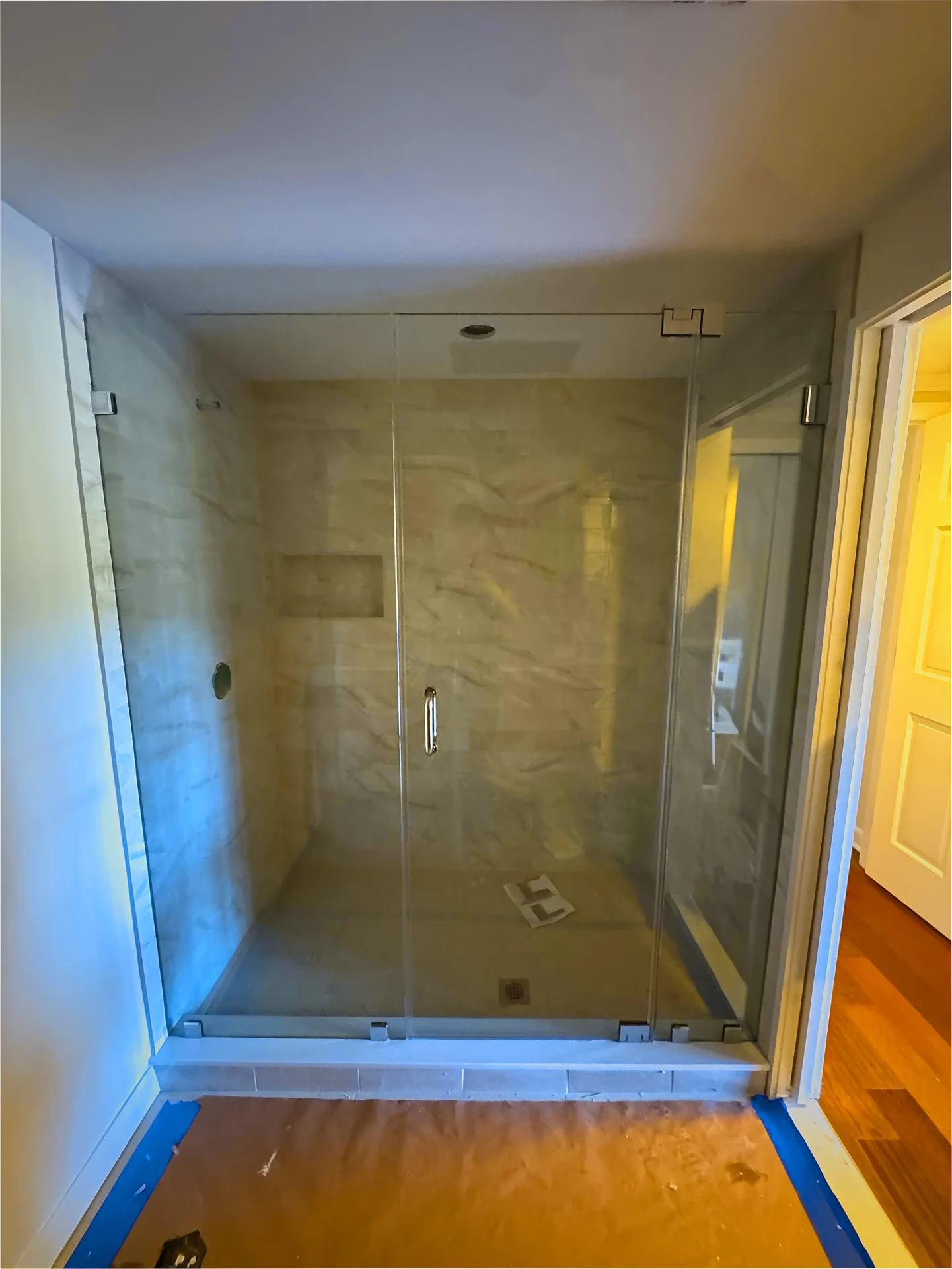 Frameless shower door installation in progress with sidelite in Newton MA
