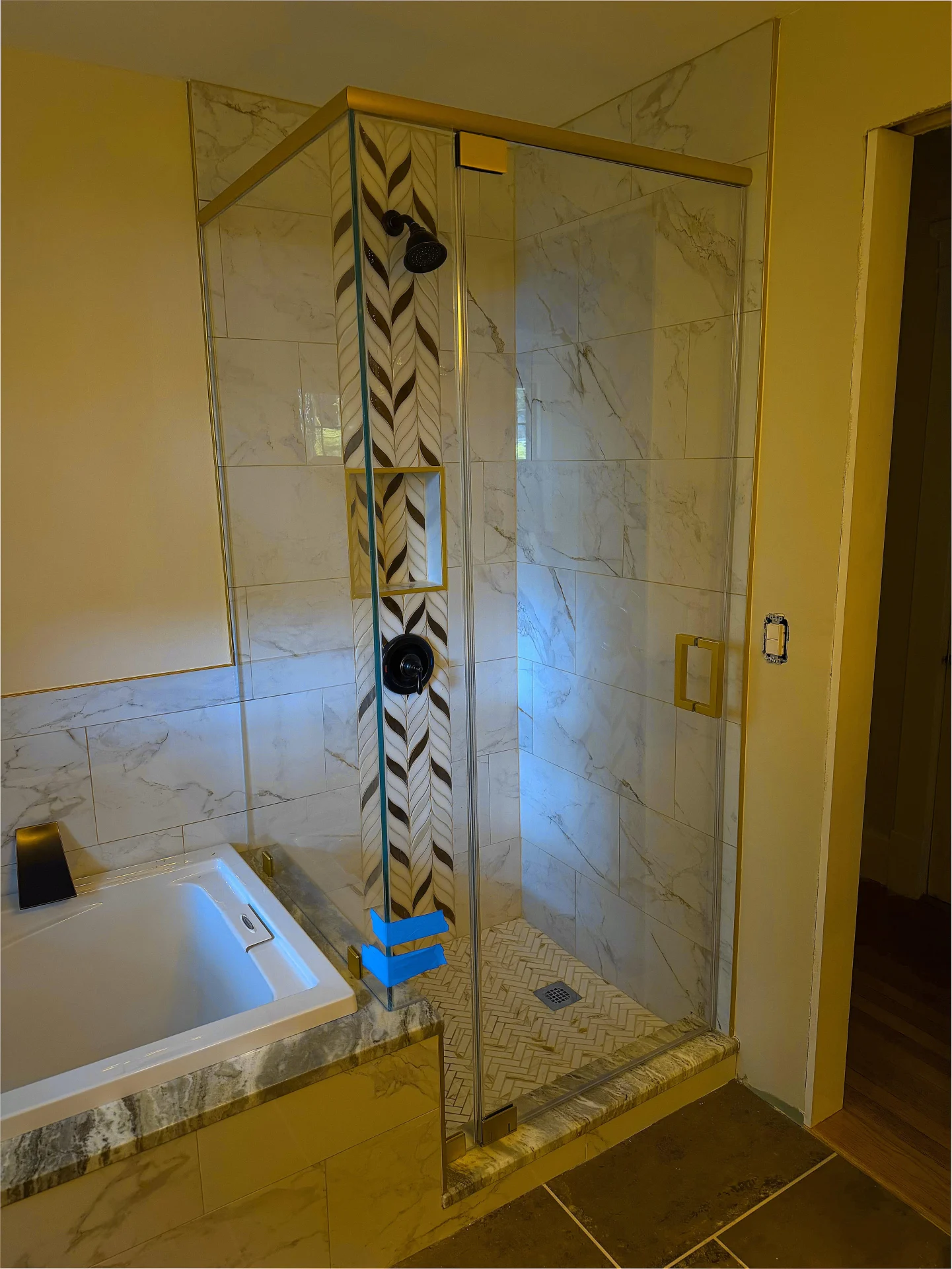 Frameless corner shower door, brushed gold hardware, marble tile, Marblehead MA