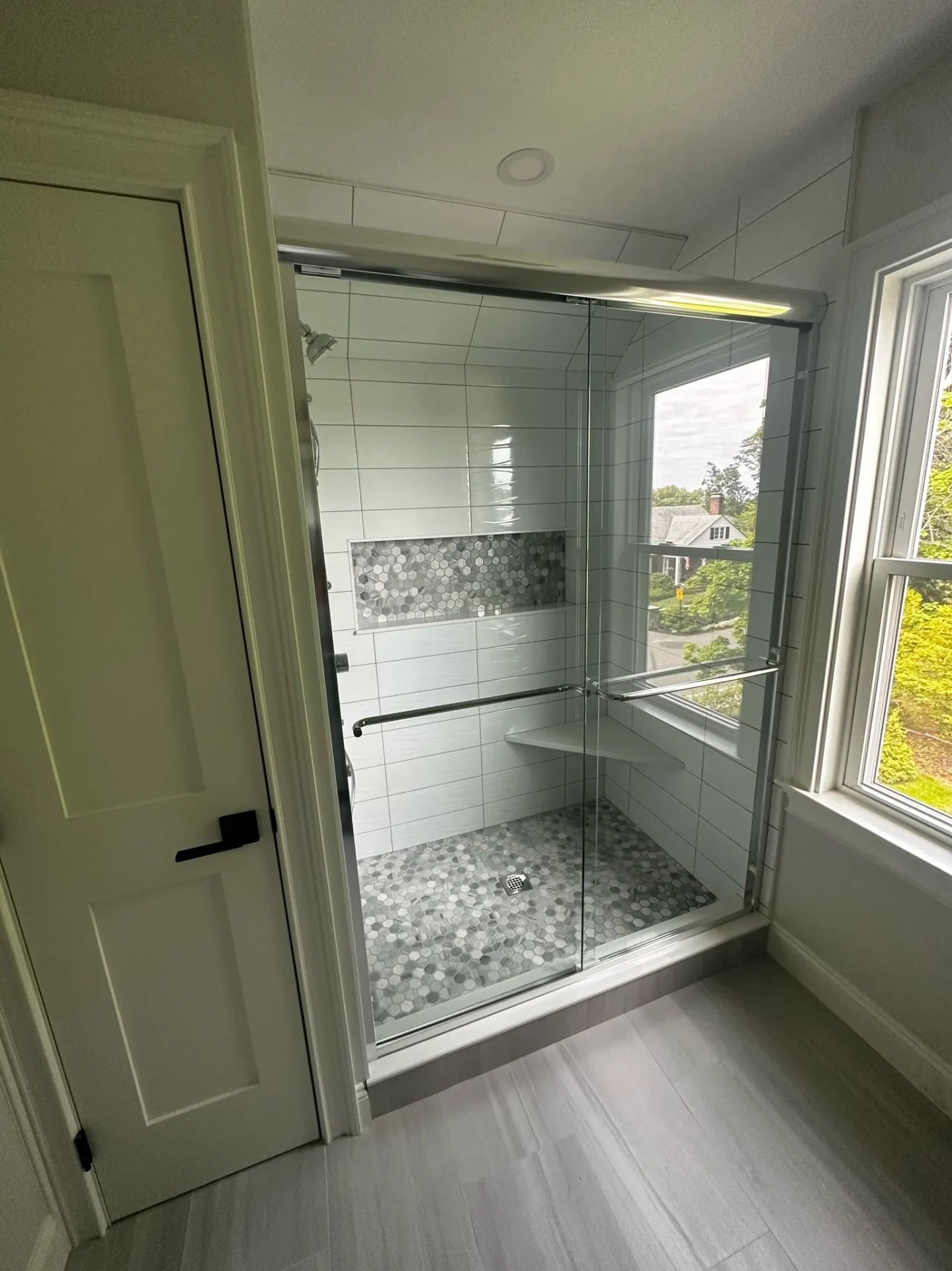 Frameless sliding shower door with chrome hardware and marble hex tile in Beverly MA