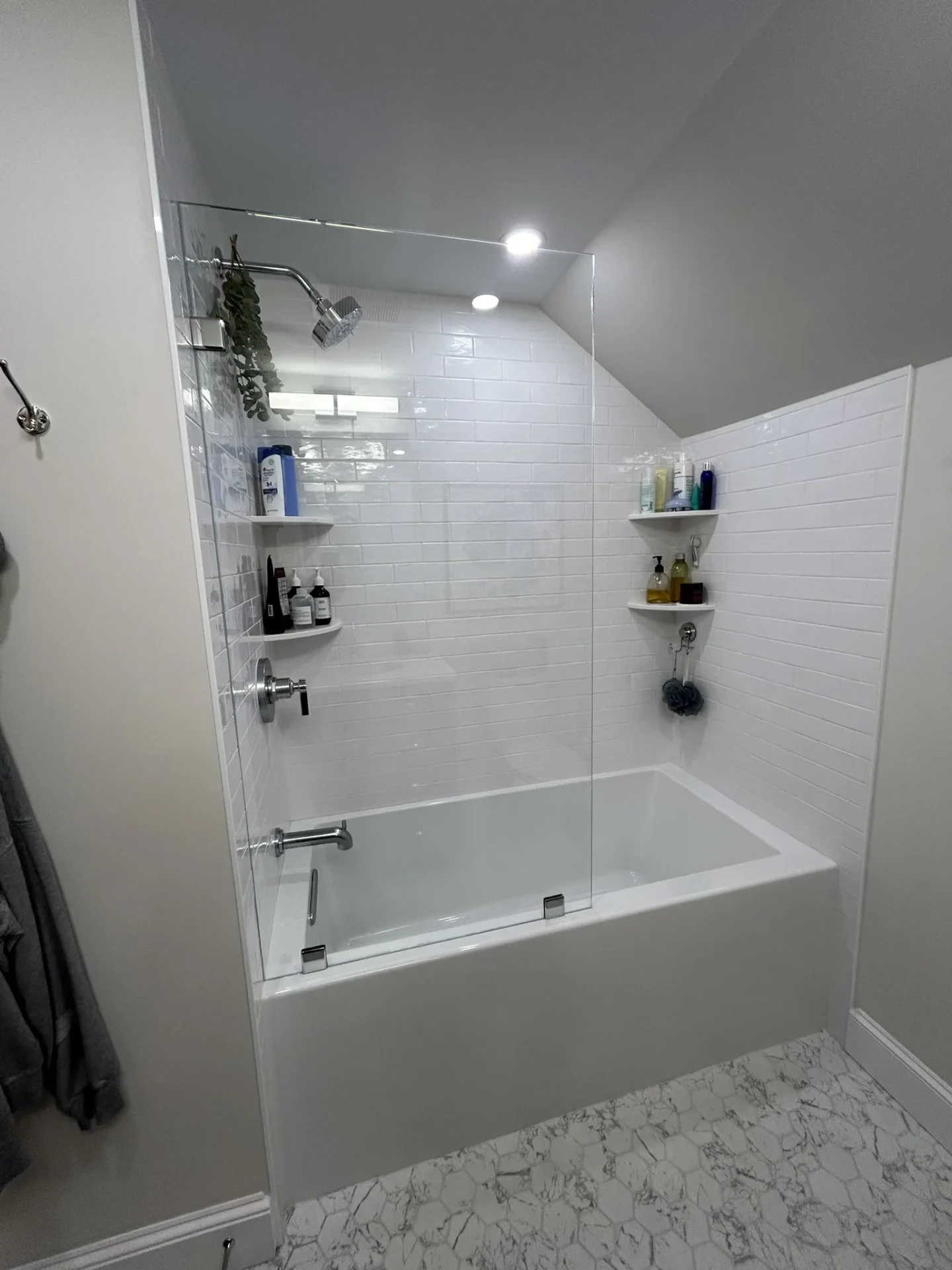 Frameless fixed shower panel over tub with chrome hardware and subway tile in Reading MA