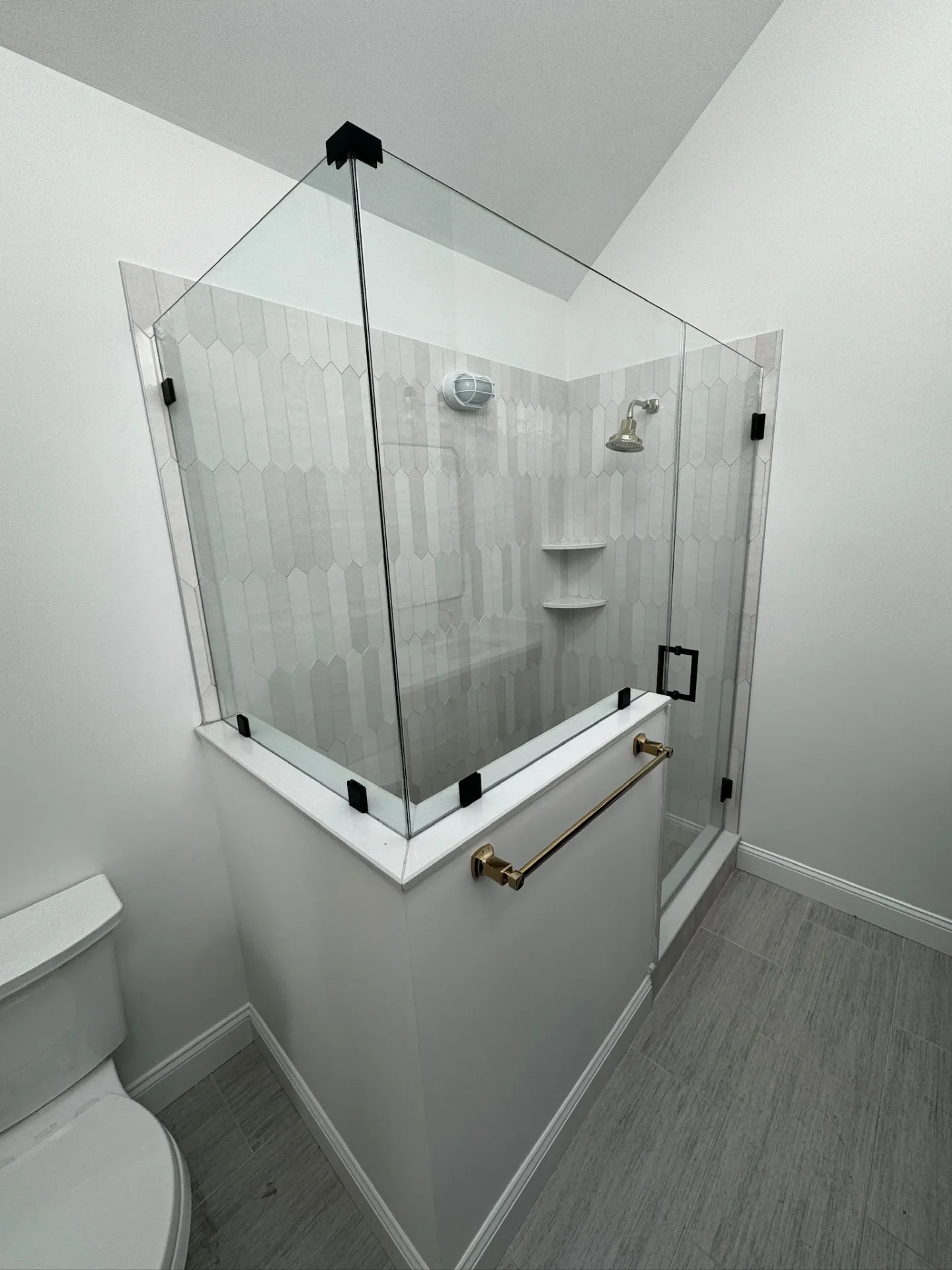 Frameless neo-angle shower door with black hardware and picket tile in Chelmsford MA