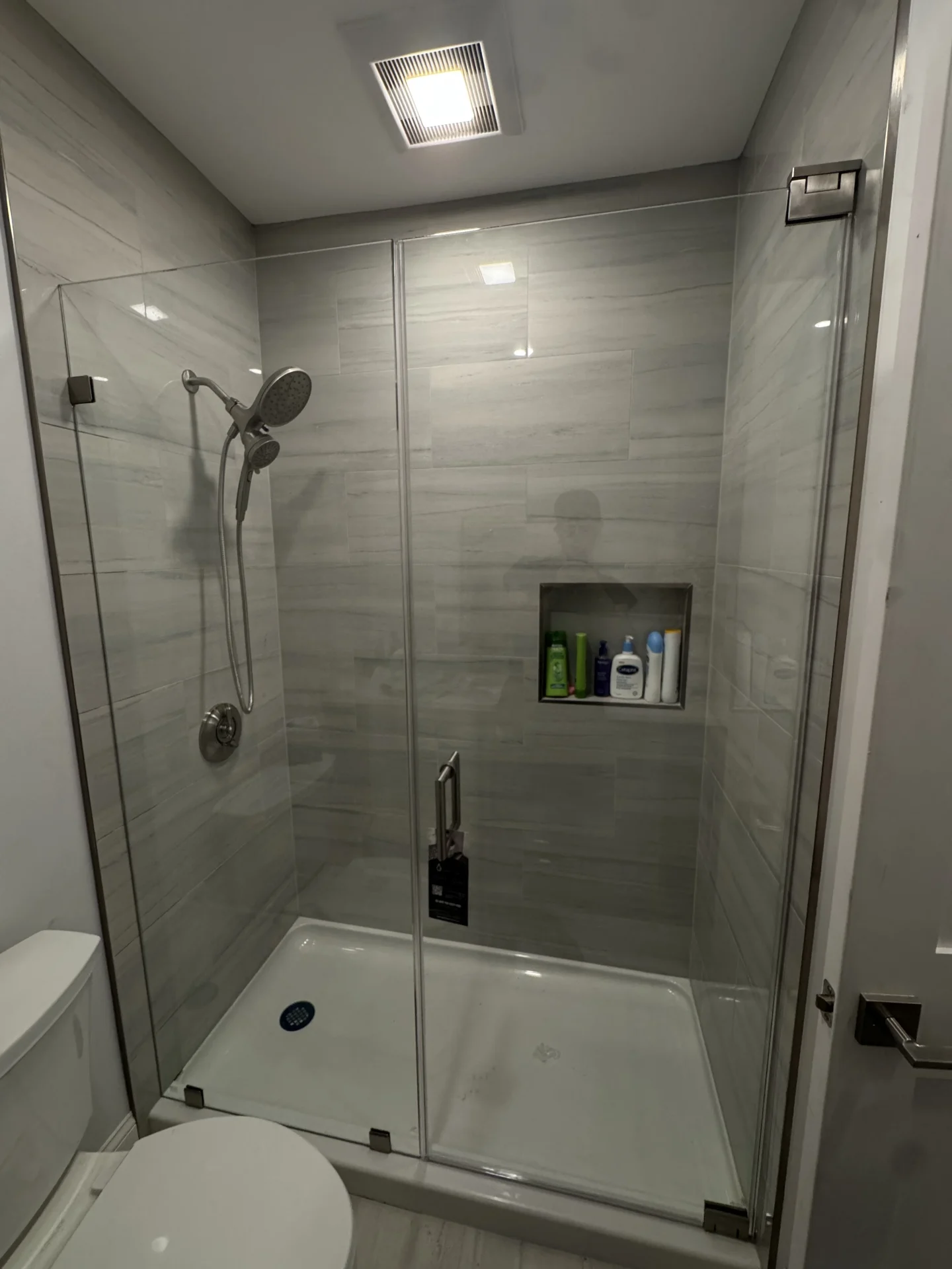 Frameless hinged shower door with brushed nickel hardware and gray tile in Boston MA