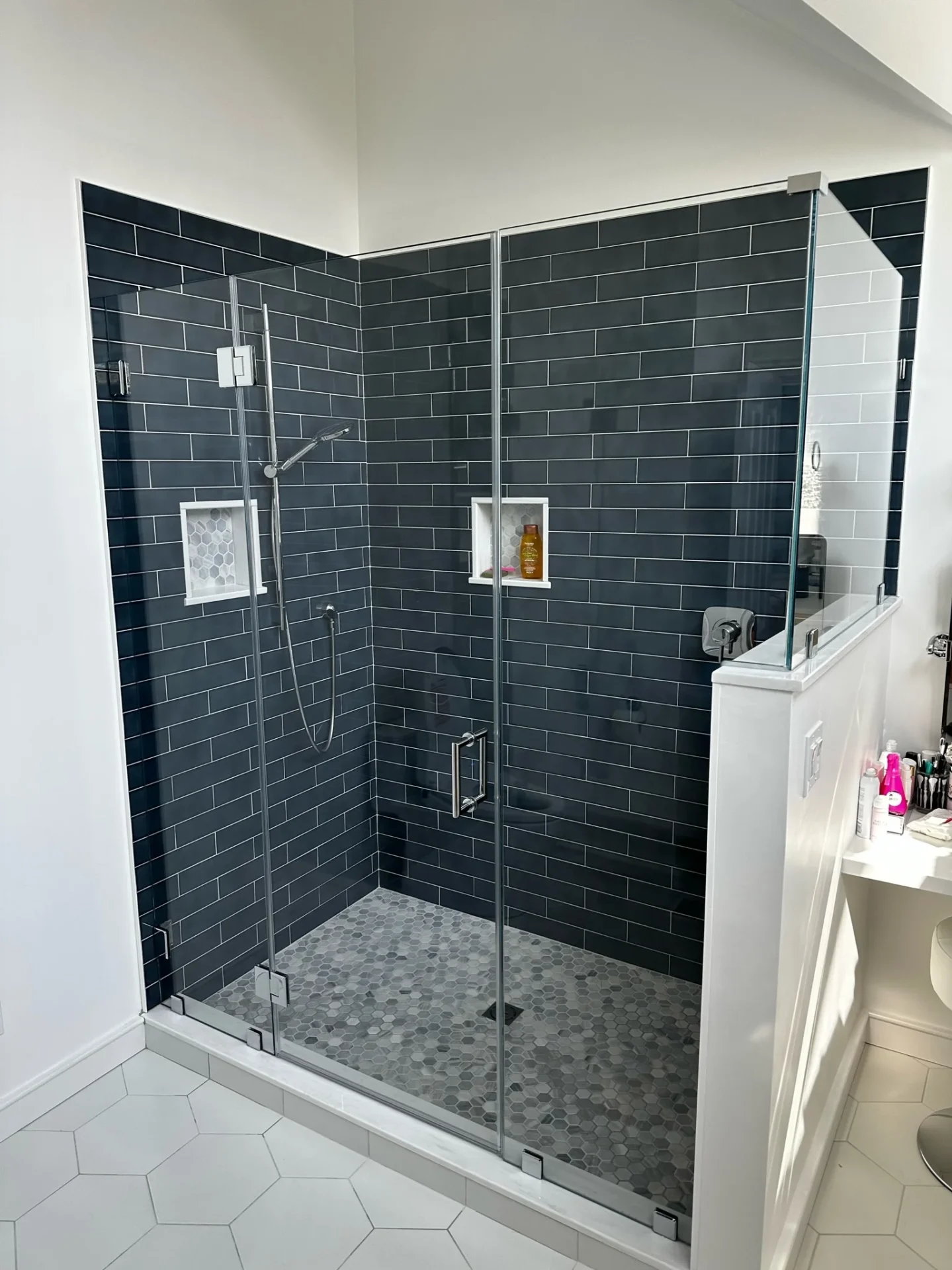 Frameless shower door with chrome hardware and navy subway tile in Marblehead MA