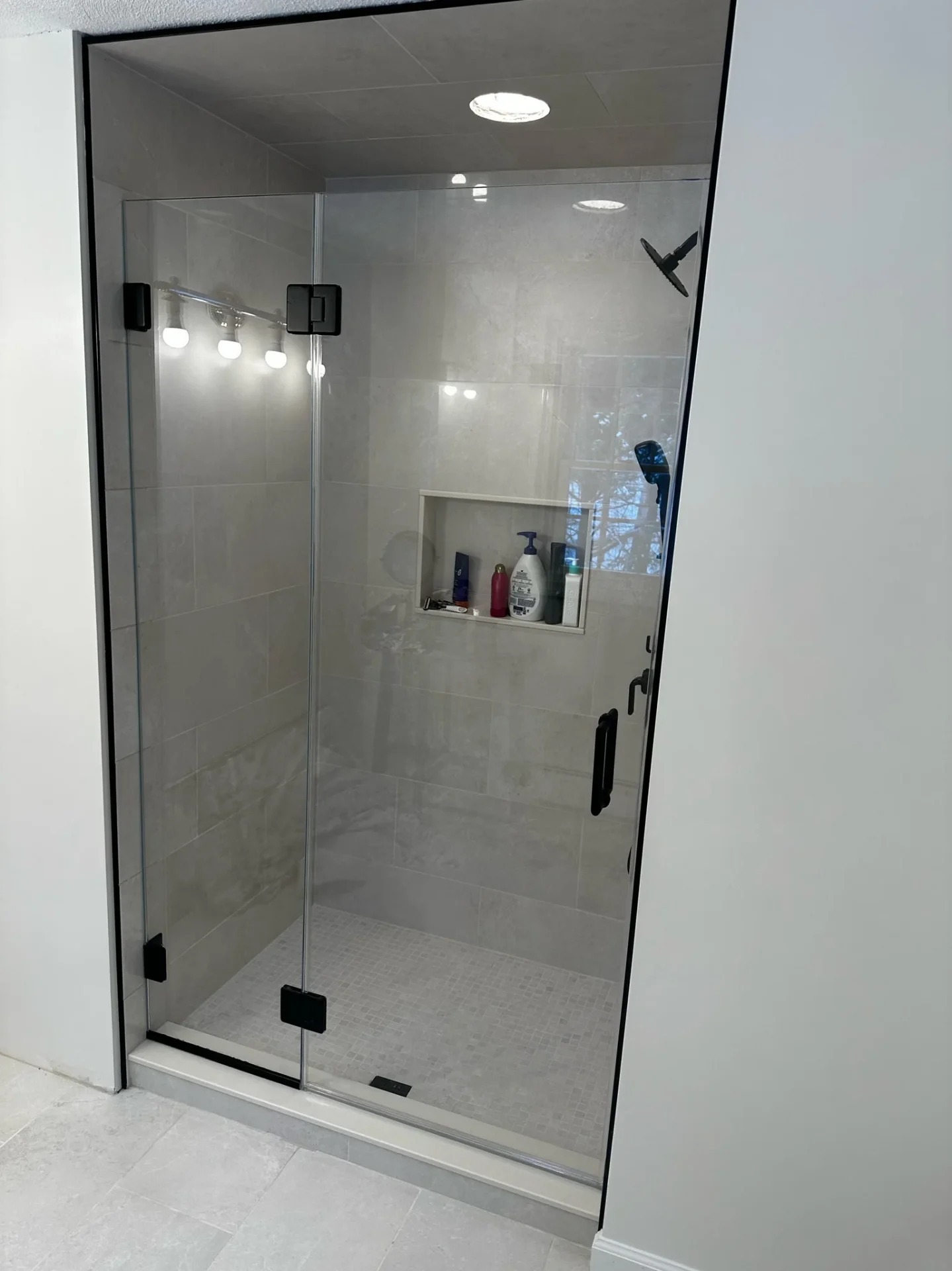 Frameless pivot shower door with matte black hardware and tiled niche, Boxford