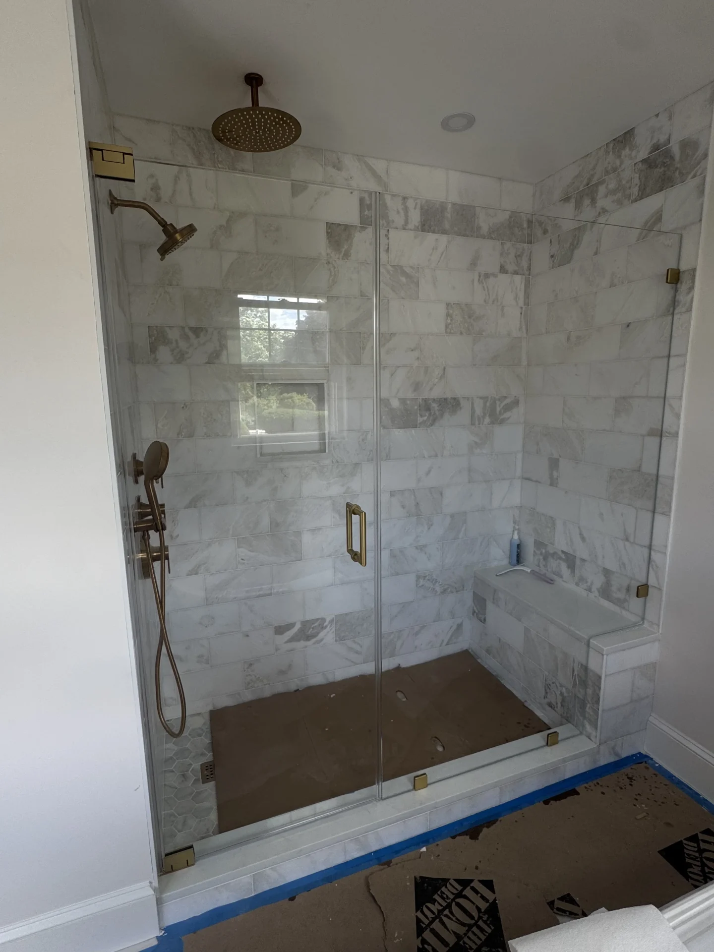Frameless swing door, antique brass hardware, marble subway tile, Salem MA