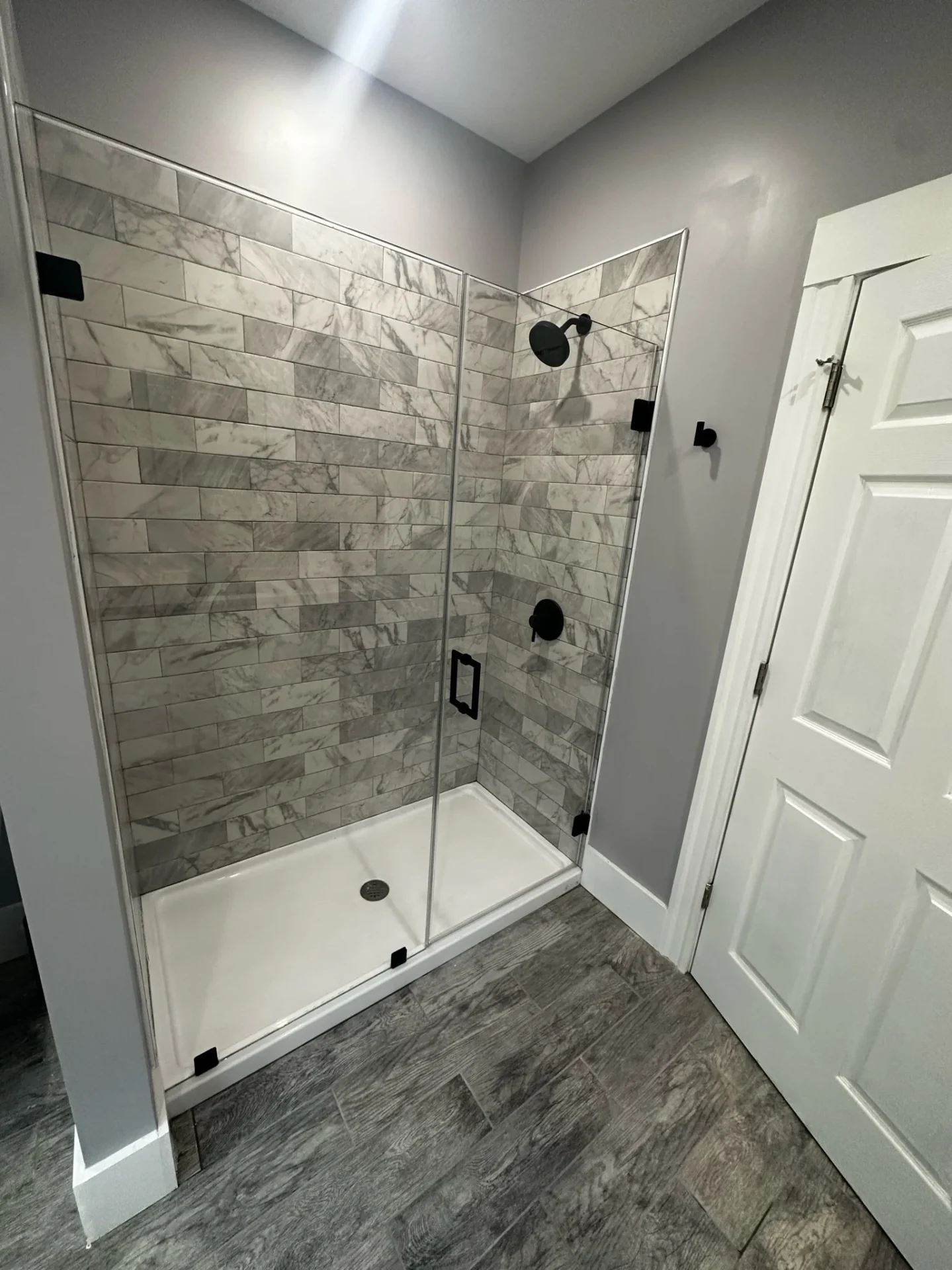 Frameless pivot shower door, matte black hardware, gray marble tile, Salem MA