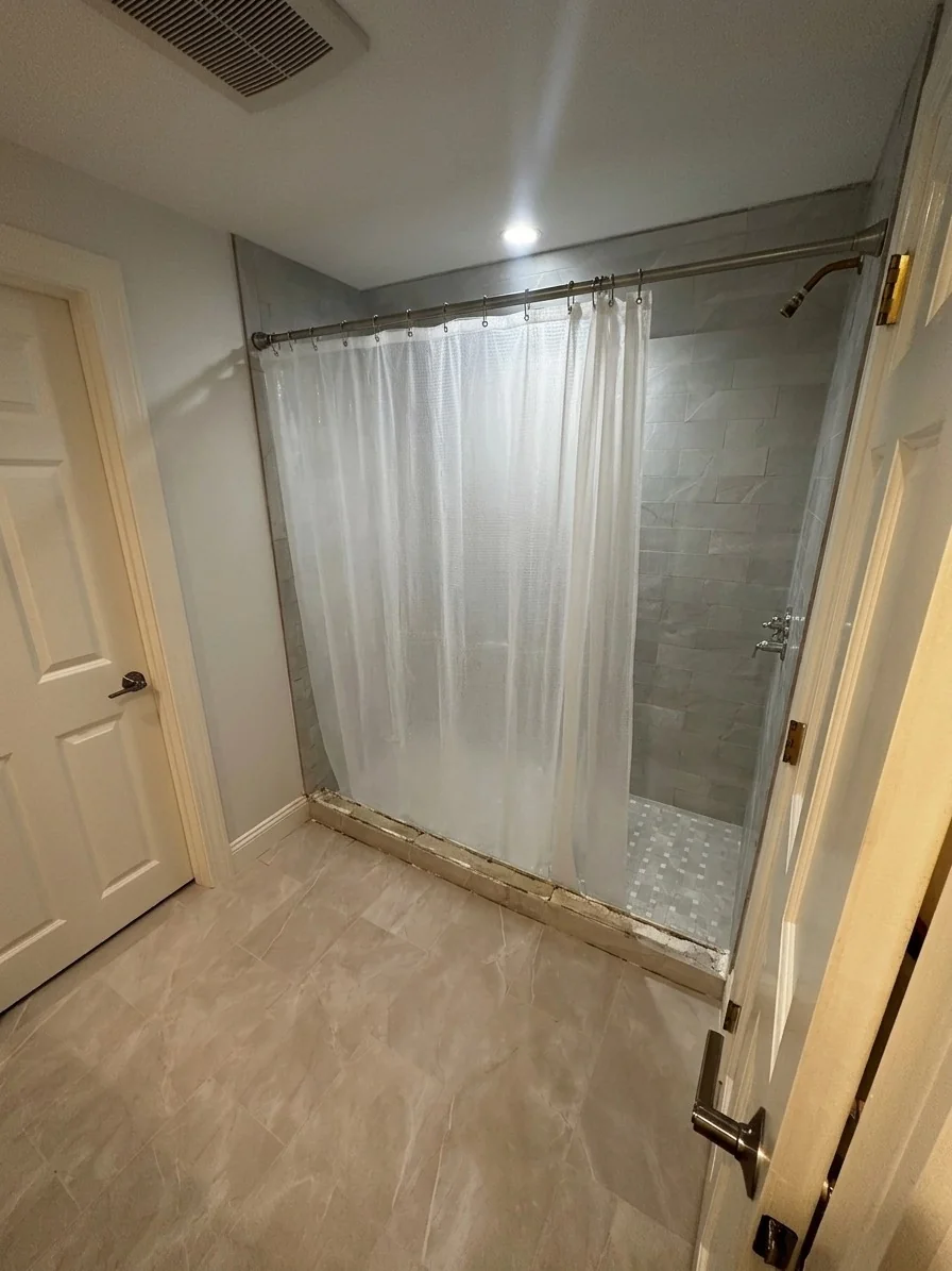 Shower stall with curtain rod and gray marble tile before frameless sliding glass door install in Wilmington, MA
